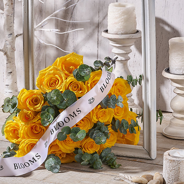 Bouquet of yellow roses with a 'Toronto Blooms' ribbon in a decorative setting.