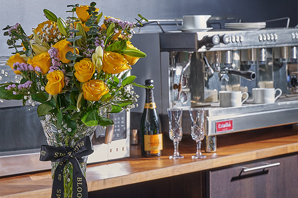 Bouquet of yellow flowers from Toronto Blooms with champagne and champagne glasses