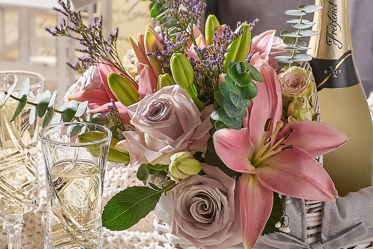 Bouquet of pink flowers with a bottle of champagne on a table by Toronto Blooms